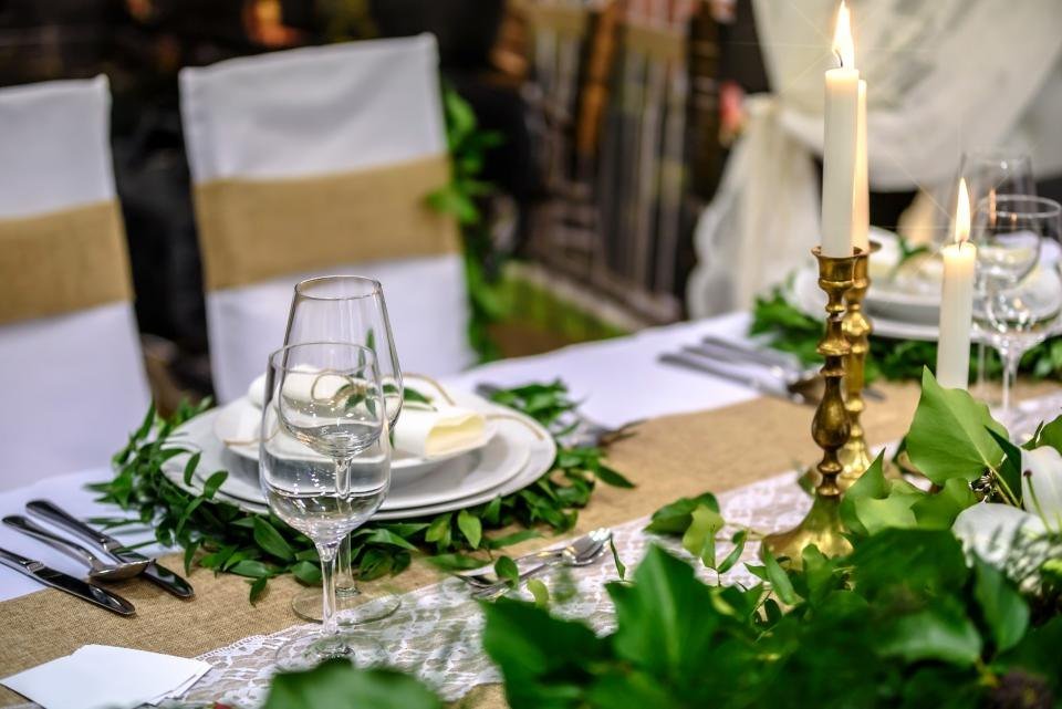 A long dinner table with candles and greenery