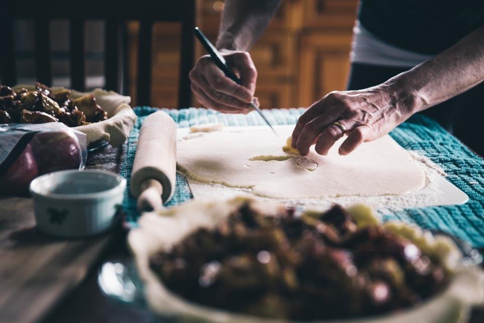 Hands preparing food at a wooden kitchen table